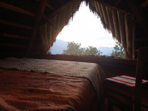 een slaapkamer met een bed en een groot raam bij Eco Albergue Azul in Cuispes
