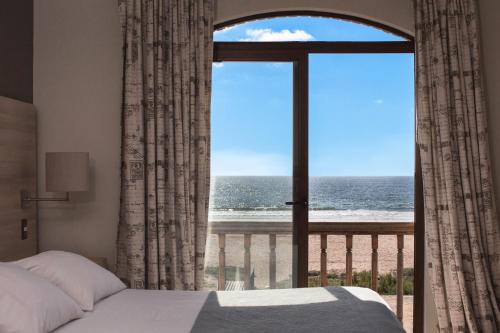 a bedroom with a bed and a view of the ocean at Hotel y Cabañas Campanario in La Serena