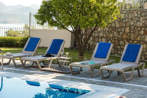 a group of four lounge chairs next to a swimming pool at Thealos Village aparthotel Lefkada in Lygia