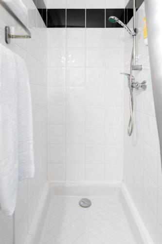 a white bathroom with a shower and a tub at Audotel in Carcassonne