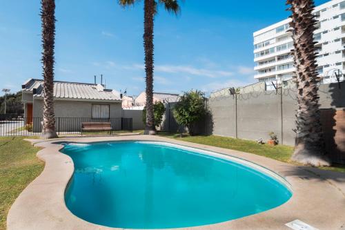 a swimming pool with palm trees and a building at Hotel y Cabañas Campanario in La Serena