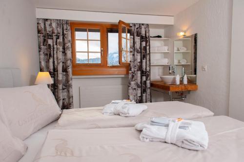 a bedroom with two beds with towels on them at Hotel Ustria Parlatsch in Trin