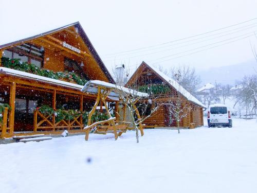 a snow covered house with a slide in front of it at Family Green in Sasovka
