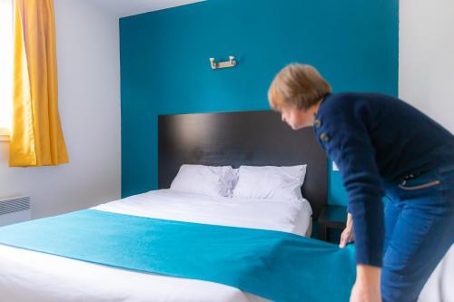 a woman is making a bed in a room at Audotel in Carcassonne