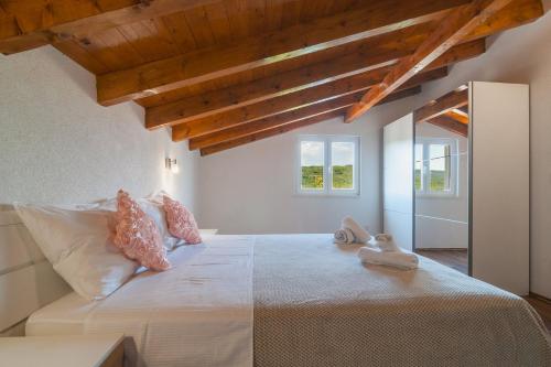 a bedroom with a large white bed with pillows at Vila M&M in Slivno