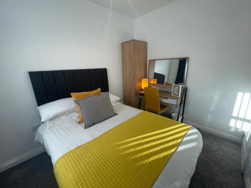 a bedroom with a large bed with a yellow blanket at Modern & cozy 2 bed bungalow in Horden