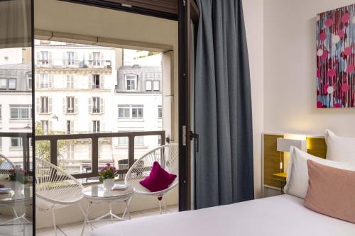 a bedroom with a bed and a balcony with a table and chairs at Hotel Paris Louis Blanc in Paris