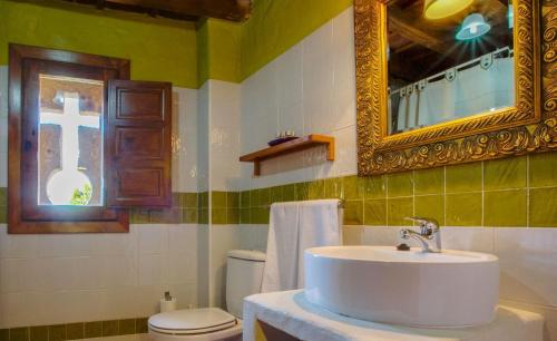 W łazience znajduje się umywalka, toaleta i lustro. w obiekcie Apartamentos Rurales Los Vergeles w mieście Valverde de la Vera