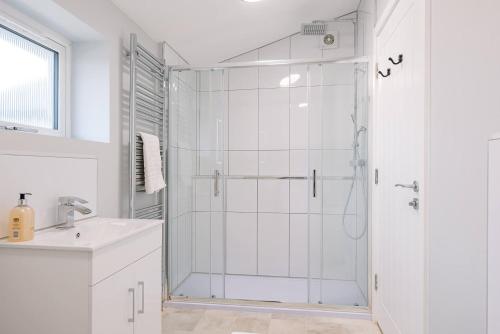 a white bathroom with a shower and a sink at 2 The Smithy in Saxmundham