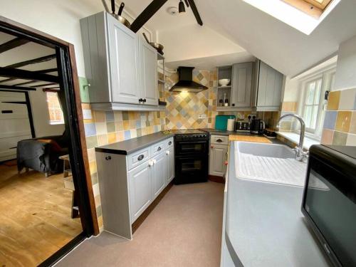 a kitchen with white cabinets and a sink at Beautiful 500 year old listed Kentish cottage in Wingham