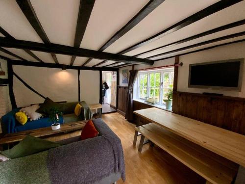 a living room with a couch and a flat screen tv at Beautiful 500 year old listed Kentish cottage in Wingham