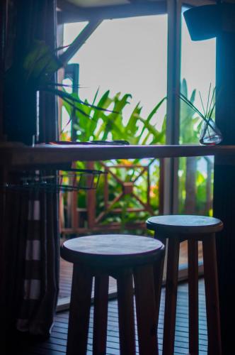 two tables and two stools in front of a window at Le Domaine du Rocher Noir in Pointe-Noire