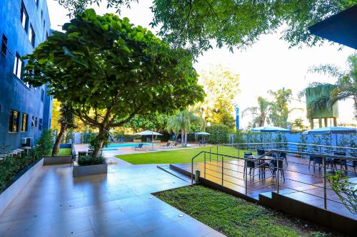 un parco con albero e tavoli e un edificio di Iguassu Express Hotel a Foz do Iguaçu