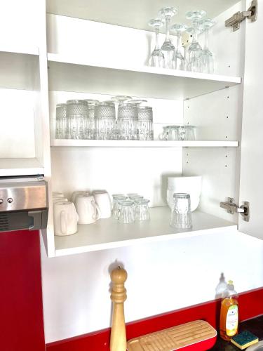 une cuisine avec des étagères blanches et des plats en verre dans l'établissement Art Apparts Chaudronniers, à Béziers