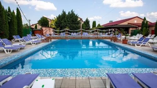 a large swimming pool with blue lounge chairs and a resort at Hotel Levisticum in Bacău