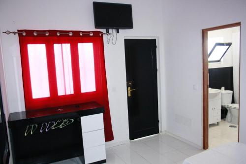 a room with a red window and a tv on a wall at Académico do Sal in Espargos