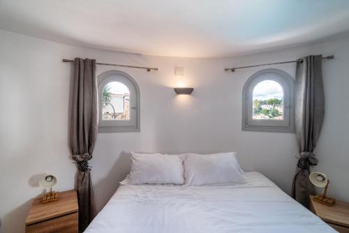 a bedroom with two windows and a bed at Casa au Lilas Rosa in Benissa