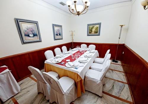 a dining room with a table and white chairs at Hotel Santa Cecilia in Ciudad Real