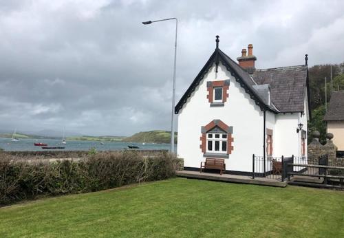 a white house with a grassy yard next to the water at Sea Lodge Holiday Home by Trident Holiday Homes in Bantry