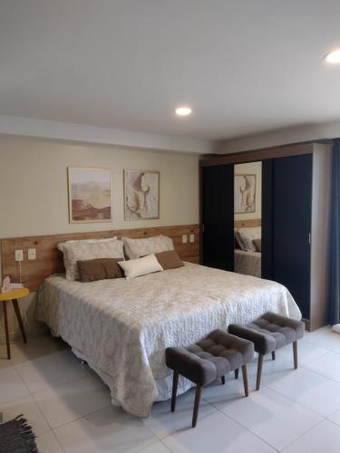 a bedroom with a large bed and two chairs at Flat do Barão Tabatinga in Conde