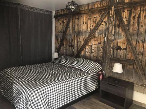 een slaapkamer met een bed en een houten muur bij Mon Coin de Pays in Sacré-Coeur-Saguenay