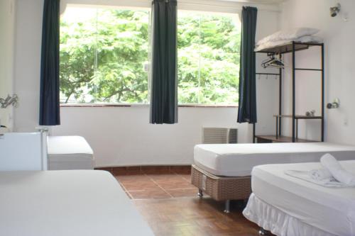 a bedroom with two beds and two windows at Farfalla São Manuel in Rio de Janeiro
