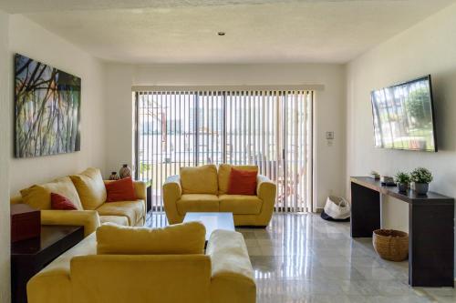 a living room with yellow furniture and a large window at Villas La Marina in Cancún