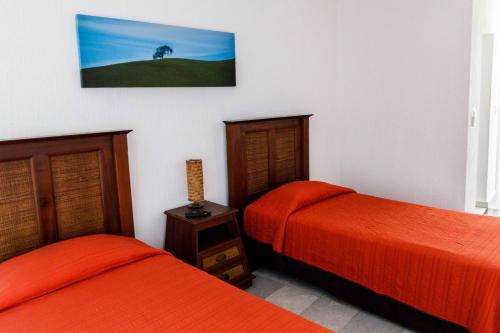 two beds in a room with orange sheets at Villas La Marina in Cancún