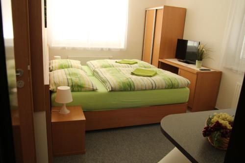 a bedroom with a bed and a desk and a television at Penzion Bobule in Staré Město