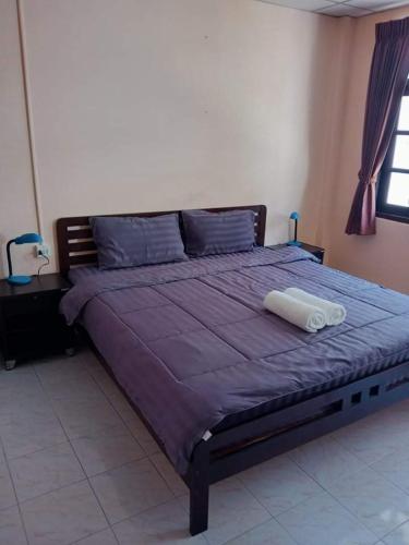 a large bed in a bedroom with a purple blanket at Stefan's Guesthouse in Jomtien Beach