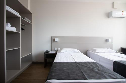 two beds in a small room with a desk at Hotel Valerim Itajaí / Navegantes in Itajaí
