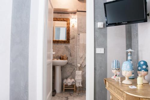 baño con lavabo y TV en la pared en BIBI BOUTIQUE AREZZO Cartazucchero - Cioccolato, en Arezzo