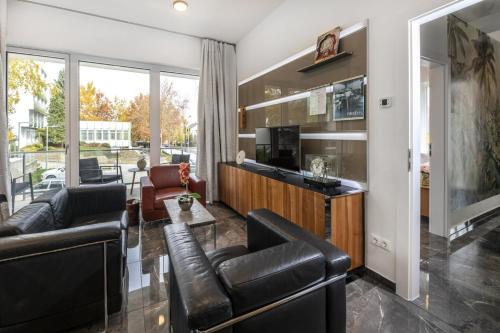 a living room with leather furniture and a large window at Flavius Spa Residence in Hévíz