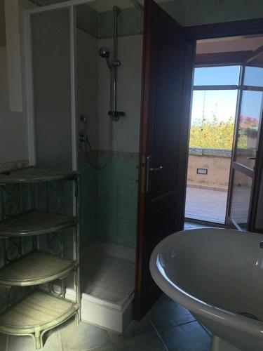 a bathroom with a tub and a shower with a window at La Cinta in San Teodoro