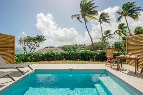 a swimming pool in a backyard with a table and chairs at Suites Anagani in Le François