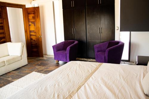 a bedroom with purple chairs and a bed and a couch at San Antonio Hotel Boutique in Santiago Matatlán