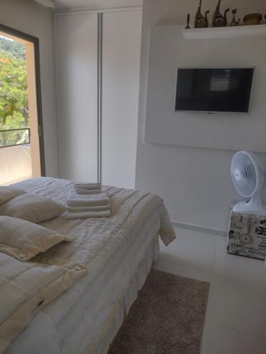 1 dormitorio blanco con 1 cama y TV en Jurerê Residencial Acacia, en Florianópolis