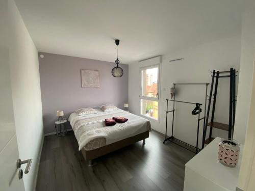 a white bedroom with a bed and a window at Appartement Orchidées proche centre Ville in Colmar