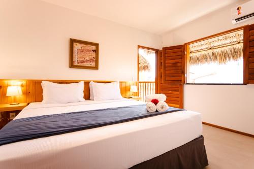 a bedroom with a bed with two teddy bears on it at UNKUÉ POUSADA FLATS in Jericoacoara