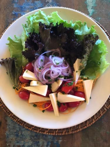 a white plate with a salad with cheese and vegetables at Pousada da Pedra Rifaina in Rifaina