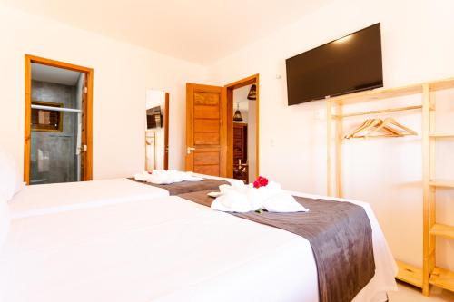 a bedroom with two beds and a flat screen tv at UNKUÉ POUSADA FLATS in Jericoacoara