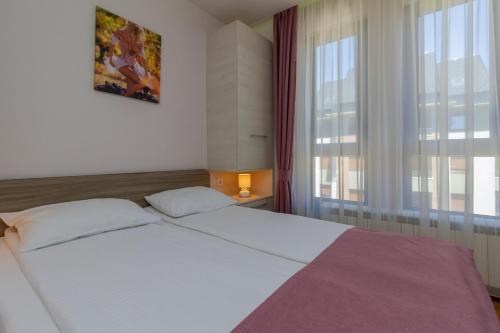 ズラティボールにあるTime Out Wine apartmanの窓のある大きな白いベッドのある寝室