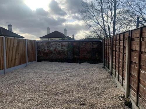 a fence next to a brick wall with a gate at 3/4 Bedroom House in Manchester