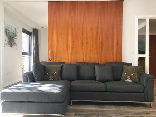 Riverside West End Apartment في غلاسكو: غرفة معيشة مع أريكة وجدار خشبي