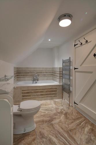 a bathroom with a toilet and a tub and a door at Katie's Cottage Bellaghy in Bellaghy
