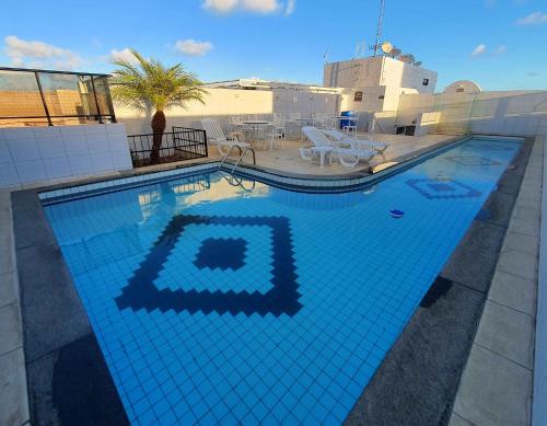 uma grande piscina com azulejos azuis em 02 QUARTOS, a 100 metros da PRAIA de PAJUÇARA em Maceió