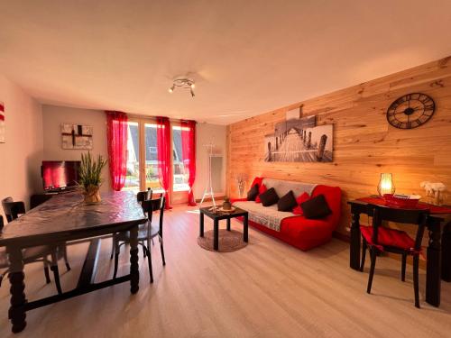 un salon avec un canapé rouge et une table dans l'établissement T2 ensoleillé. Terrasse et vaste jardin commun, à Cauterets