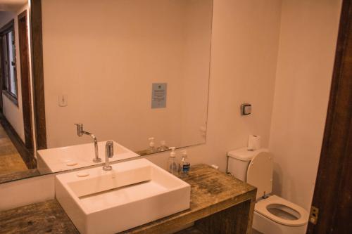a bathroom with a white sink and a toilet at The Eco Palace Hostel in Búzios