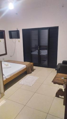 a bedroom with a bed and a tv and a couch at Hostel da Moda in Passos