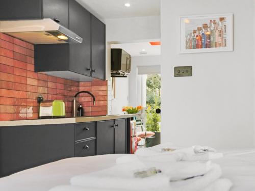 a kitchen with black cabinets and red tiles at Tiny House with Parking & Patio by Cool Bloo in Brighton & Hove